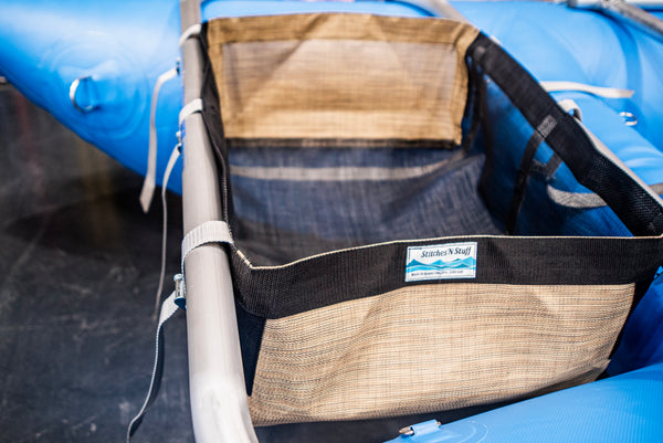A black drop bag with tan heavy duty sides attached to a blue Rocky Mountain Rafts raft.