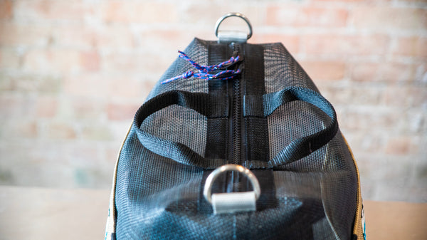 A black mesh boaters briefcase showing the d-rings, carry handles, and zipper pulls