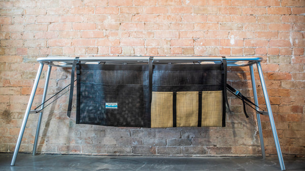 A tan and black mesh dish dryer attached to a raft table. 