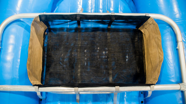 A black mesh drop bag with heavy-duty  Tan side panels, designed for rigging gear on a raft, displayed on a blue Hyside raft.