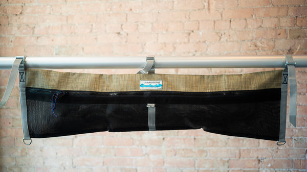 Tan and black mesh raft frame storage bag with full length zipper and three cam buckle attachments for securing to raft frame. 