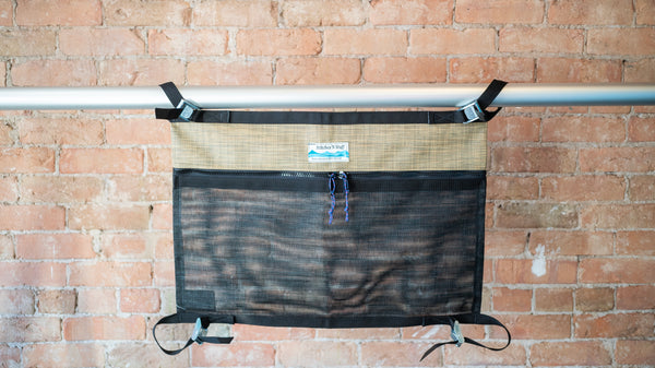 Tan and black mesh storage bag for use rafting displayed on a raft frame