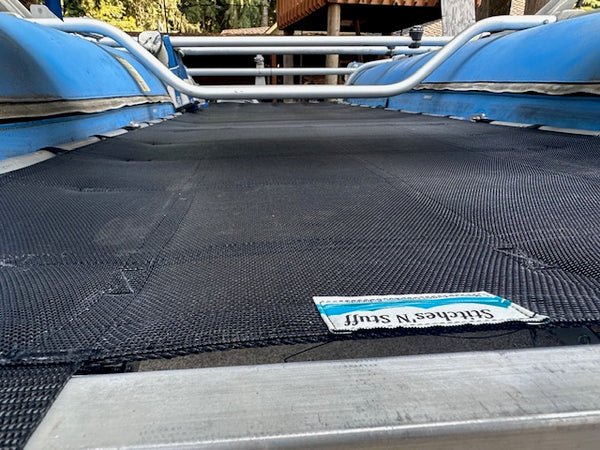 A close-up view of a custom cataraft floor made from black mesh and heavy duty webbing, displayed on a blue cataraft and raft frame. 
