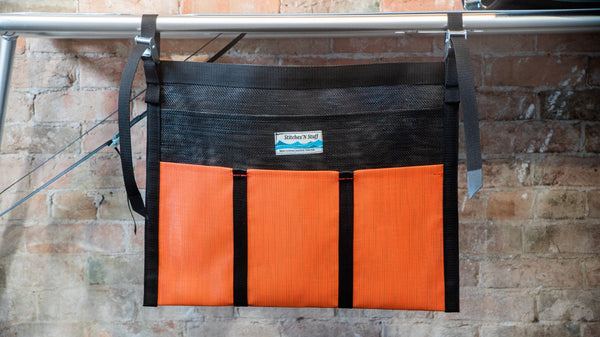 An orange and black mesh dish dryer attached to a raft table. 