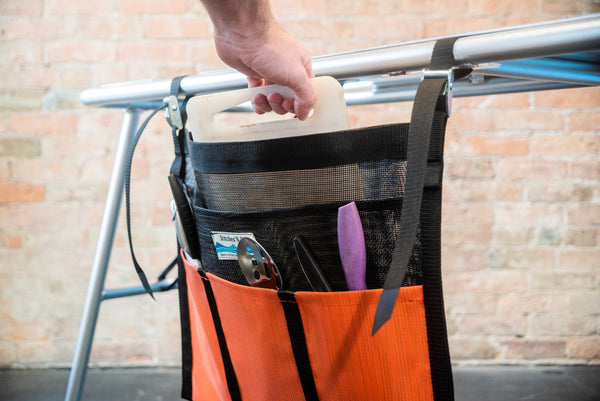 An orange and black mesh dish dryer displaying utensils drying and attached to a raft table. 