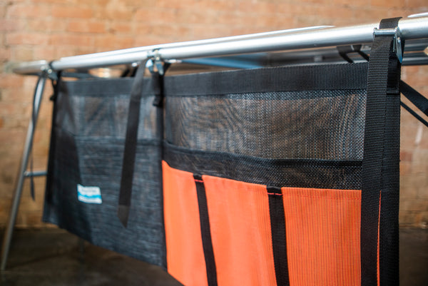 An orange and black mesh dish dryer attached to a raft table. 
