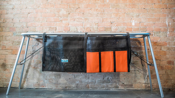 An orange and black mesh dish dryer attached to a raft table. 