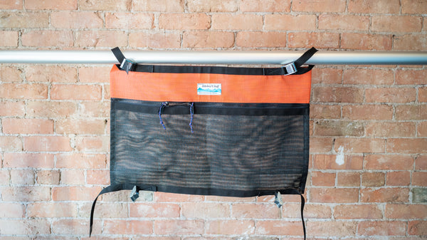 Orange and black mesh storage bag for use rafting displayed on a raft frame