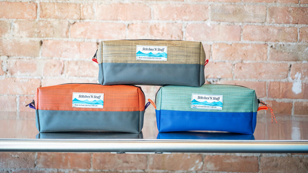 Three small rectangular storage bags stacked on a river table. 