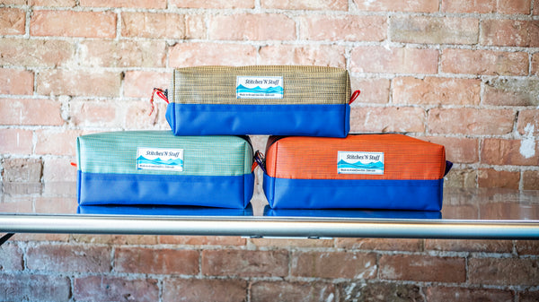 Three small rectangular storage bags stacked on a river table. 