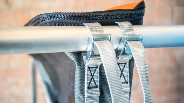 Close up of black and orange mesh bag showing cam strap attachments to a raft frame.
