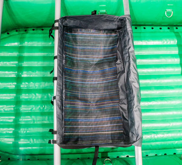 A grey heavy duty drop bag with the lid copen attached to a raft frame on a green raft. 