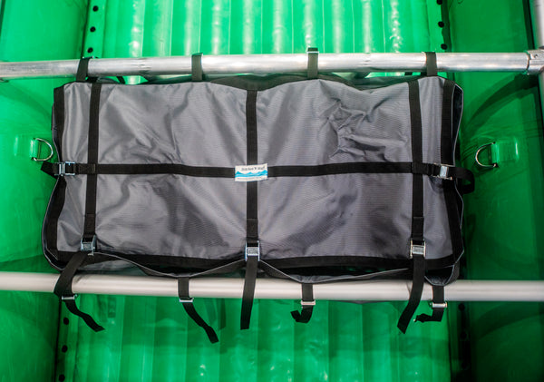 A grey heavy duty drop bag with the lid closed attached to a raft frame on a green raft. 