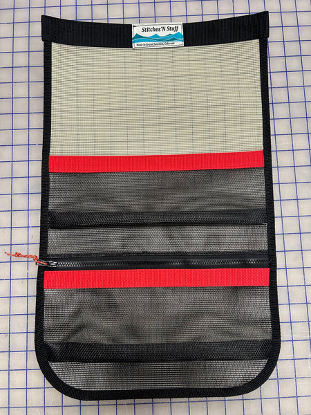 A tan and black mesh storage cubby with red webbing for use in truck campers