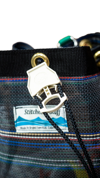 Close up of mesh round bottom bag showing stainless steel D-ring and cinch closure. 