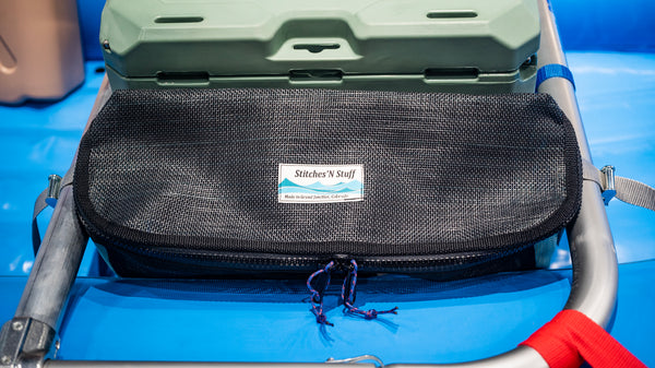 Black and green mesh bag sitting on a blue Hyside raft attached to the raft frame next to a cooler showing the 3/4 zipper opening. 
