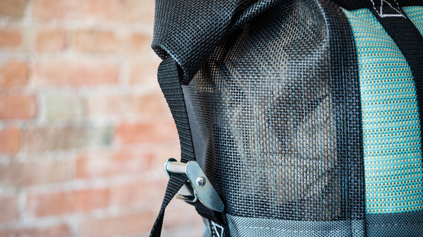 Black and green mesh bag showing the cam buckle lid attachment on the side of the bag. 