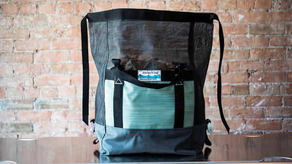 Black and green mesh bag showing the lid completely open to show the versatility of items the bag can carry. 