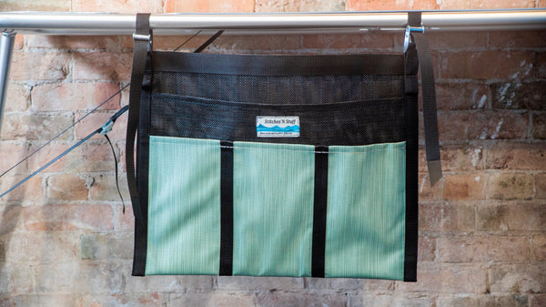 A green and black mesh dish dryer attached to a raft table. 