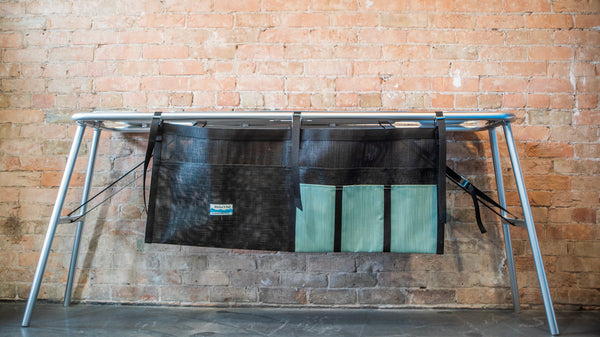 A green and black mesh dish dryer attached to a raft table. 