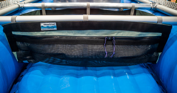 A Black and orange mesh drop bag with a zippered pocket in the front attached to a raft frame on a blue Hyside boat. 