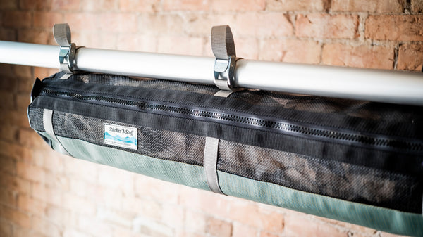 Green and black mesh raft frame storage bag with full length zipper and three cam buckle attachments for securing to raft frame. 