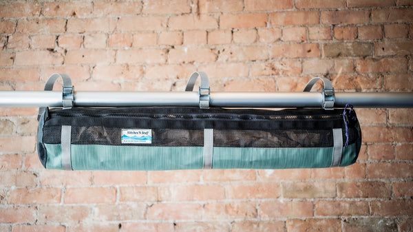 Green and black mesh raft frame storage bag with full length zipper and three cam buckle attachments for securing to raft frame. 
