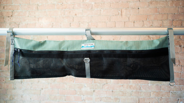 Green and black mesh raft frame storage bag with full length zipper and three cam buckle attachments for securing to raft frame. 