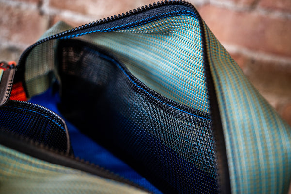 A green rectangular storage bag showing the black mesh internal pocket with the zipper open. 