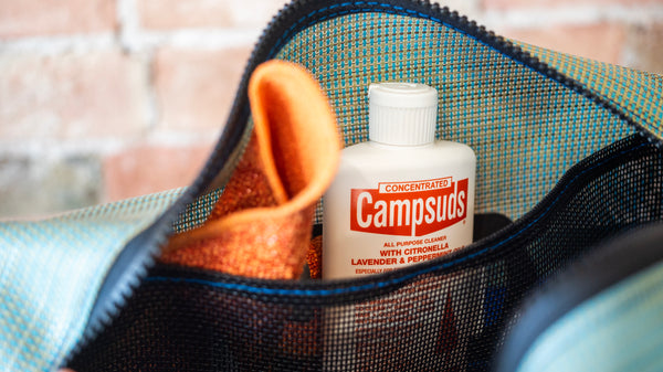 Camp Suds bottle inside a mesh pouch with a towel and other items.