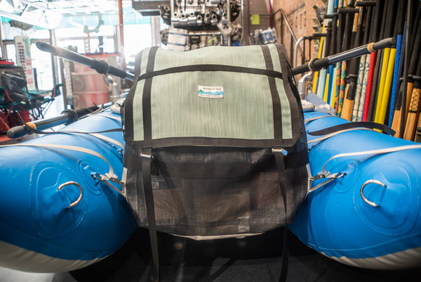 Green and black mesh bag strapped with grey webbing to a blue cataraft. 