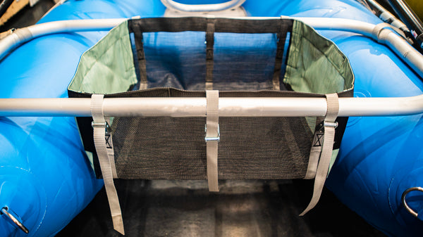 A black drop bag with green heavy duty sides attached to a blue Rocky Mountain Rafts raft.