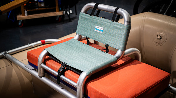 Green cover for raft captains seat on a raft frame and tan raft. 