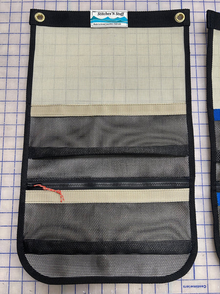 A tan and black mesh storage cubby with tan webbing for use in truck campers