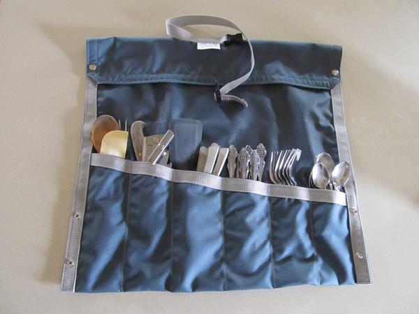 A blue utensil stow with multiple slots, displaying various utensils such as knives and forks, against a white background.