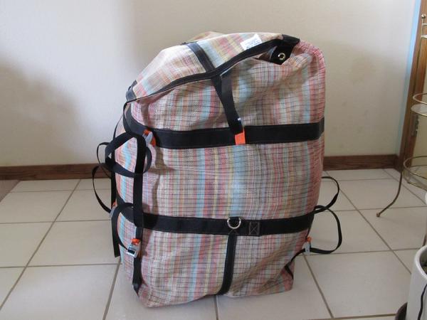 Mesh storage bag for catarafts with closed lid shows stainless steel D-rings and attachment straps. 